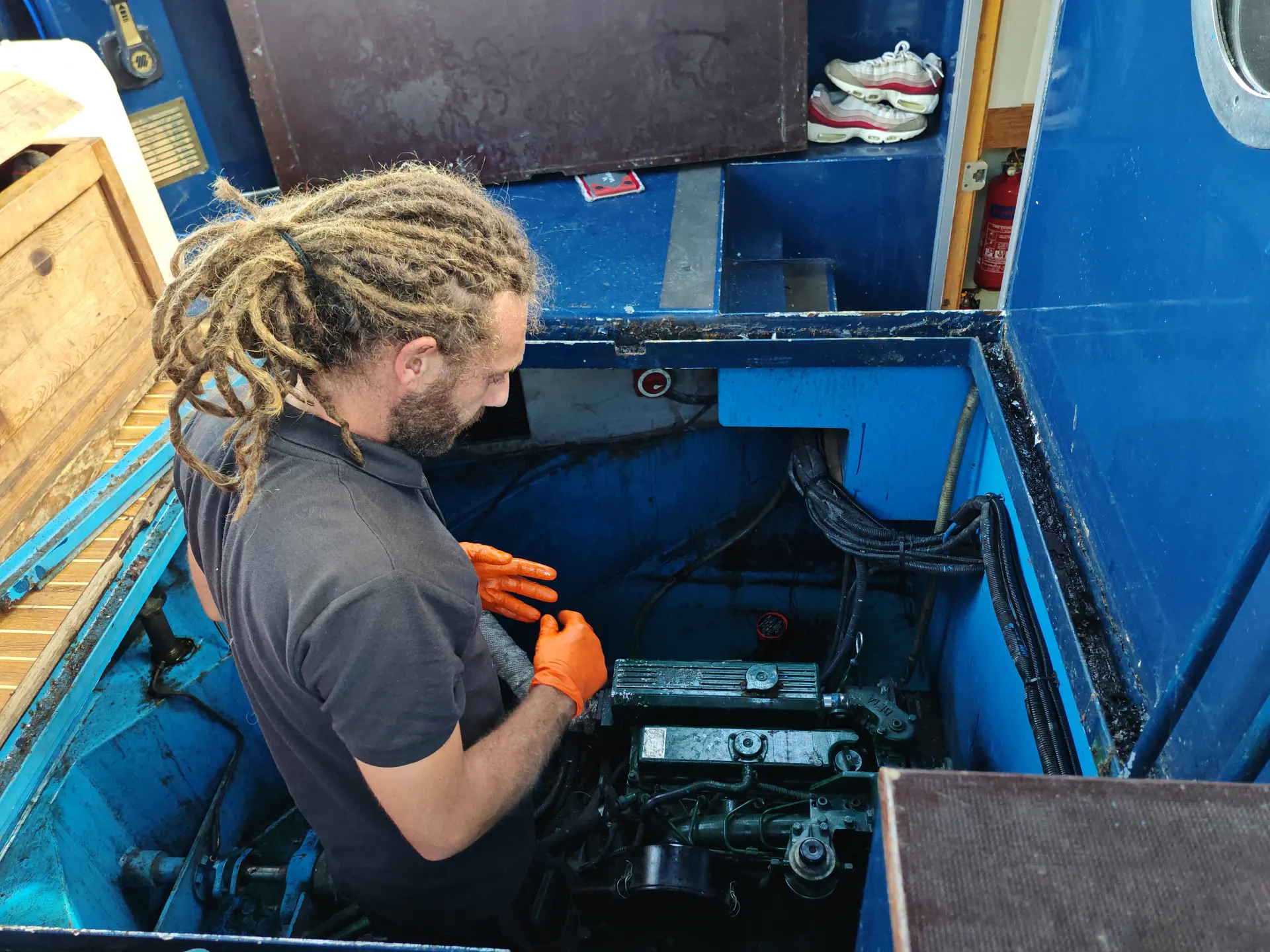 Oli working in the engine bay of a Thames boat servicing a marine diesel.