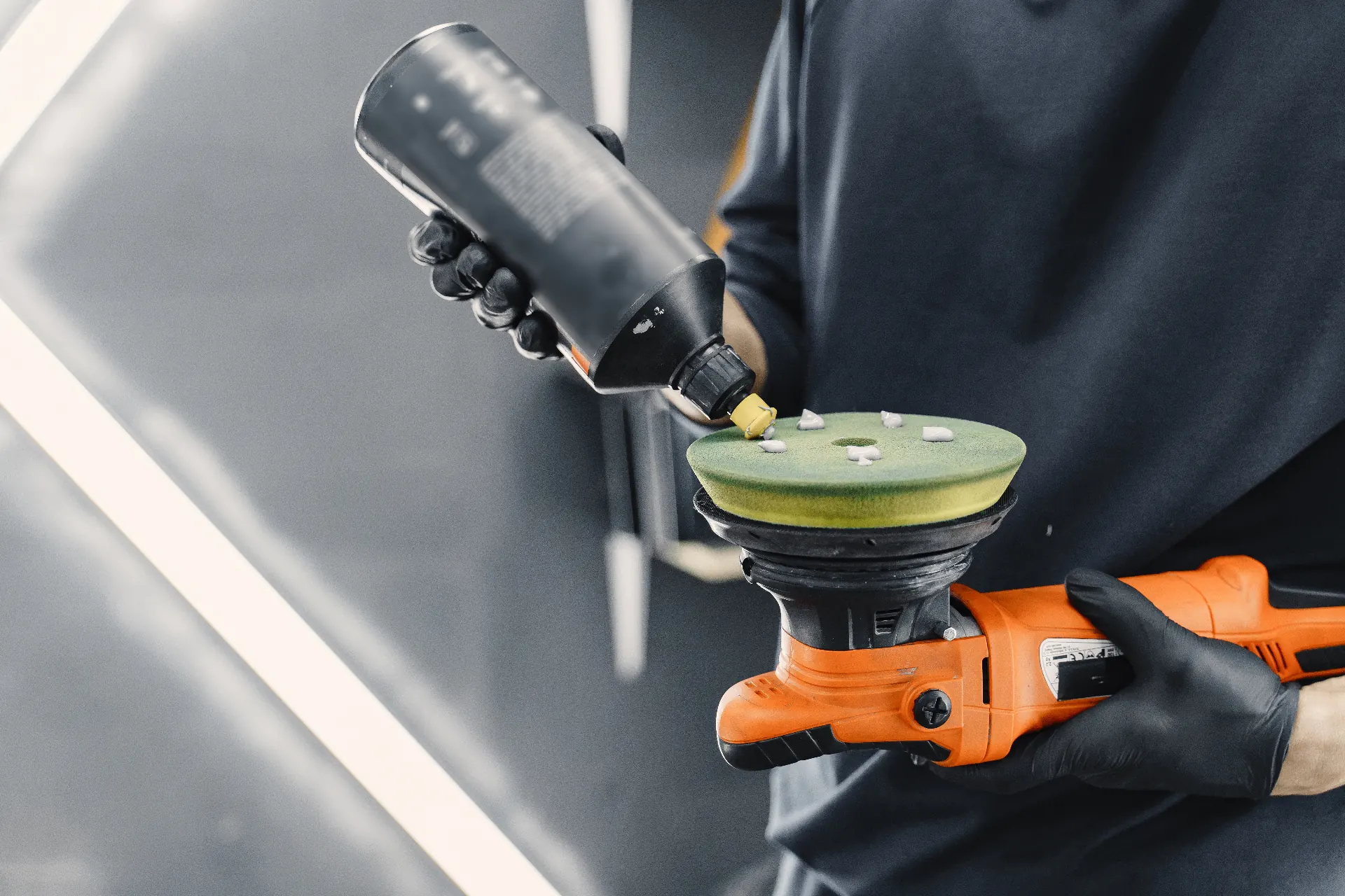 Technician applying polishing compound to a foam pad before machine polishing.