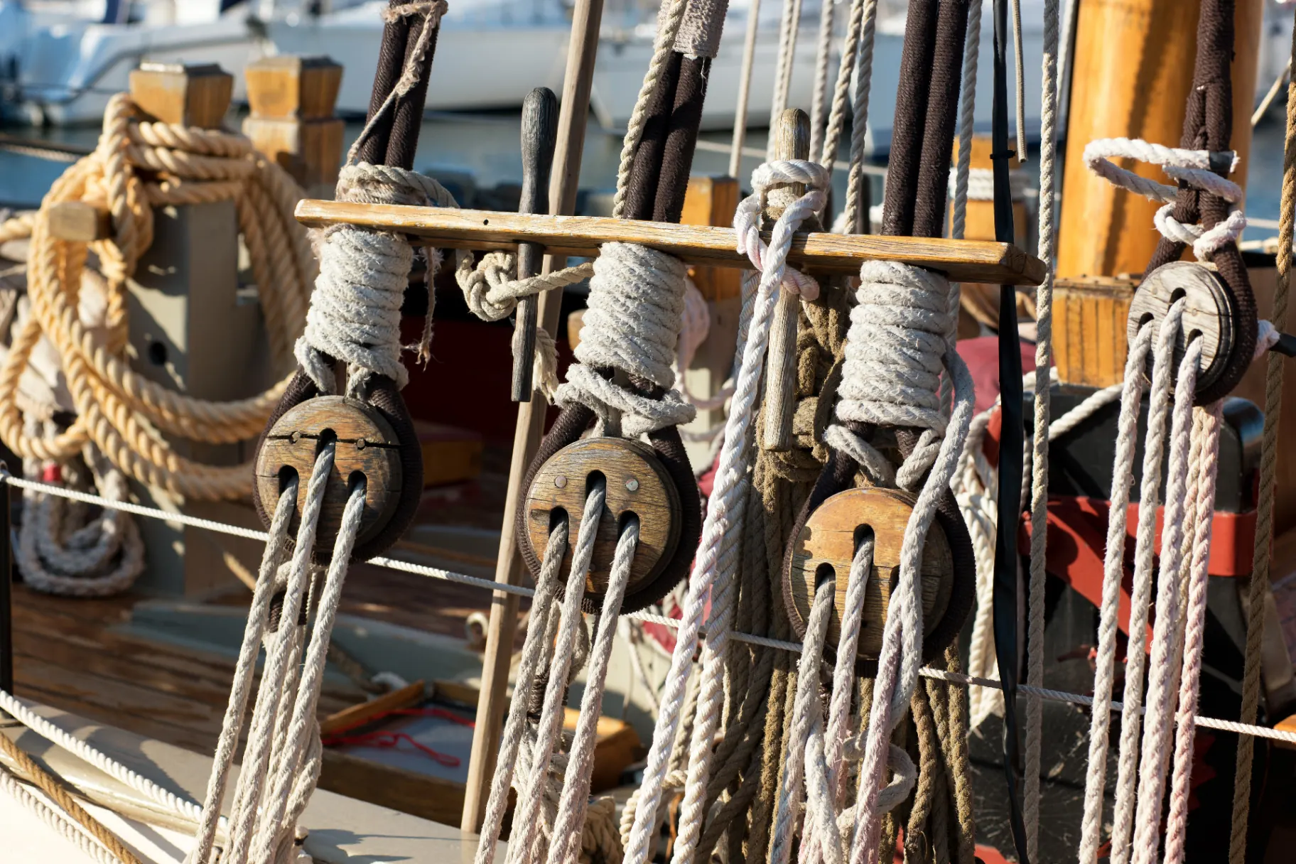 Close-up of traditional rigging ropes, blocks, and pulleys on a moored sailing boat.