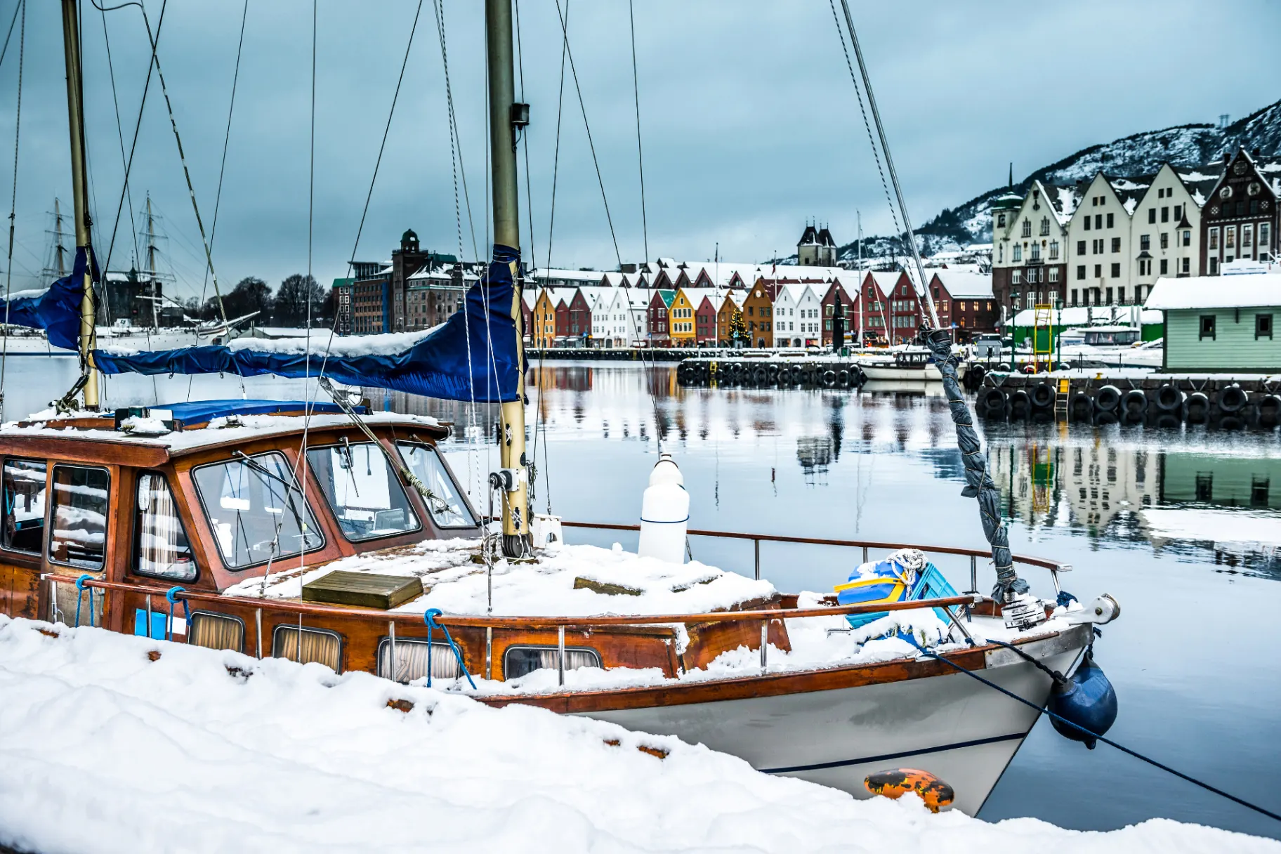 Wooden boat moored in a snow-covered harbour during winter lay-up.